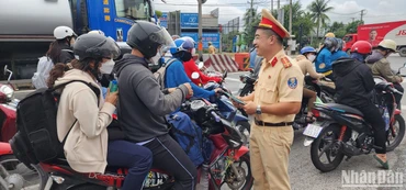Trạm Cảnh sát giao thông Tân Túc phát tờ rơi tuyên truyền và tổ chức tặng nước suối, khăn lạnh cho người dân về quê nghỉ lễ.