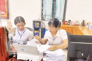 Đồng chí Phạm Thị Thúy (bên phải) cùng đồng nghiệp ở lại sau giờ làm việc tiếp tục nghiên cứu hồ sơ giúp nhân dân hoàn thành các thủ tục hành chính tại Trung tâm Phục vụ hành chính công.