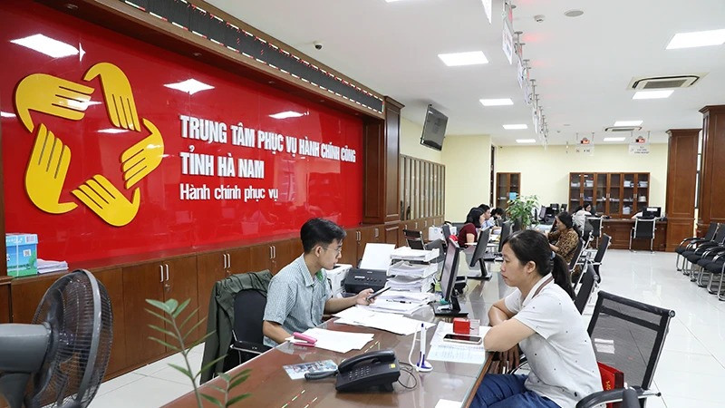 Cán bộ, công chức Trung tâm hành chính công tỉnh Hà Nam giải quyết thủ tục hành chính cho người dân. (Ảnh ĐÀO PHƯƠNG)