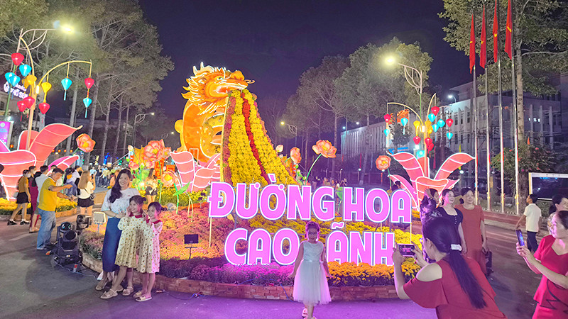 Du khách rất thích thú ngắm và chụp ảnh bên linh vật rồng, ngay đầu đường hoa. Ảnh: HỮU NGHĨA