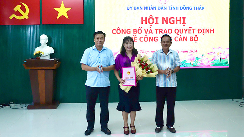 Phó Chủ tịch Ủy ban nhân dân tỉnh Đồng Tháp Nguyễn Phước Thiện (bìa trái) trao quyết định, Giám đốc Sở Nội vụ Phan Hữu Phước tặng hoa chúc mừng nhà báo Ngô Thị Ngọc Hạnh.