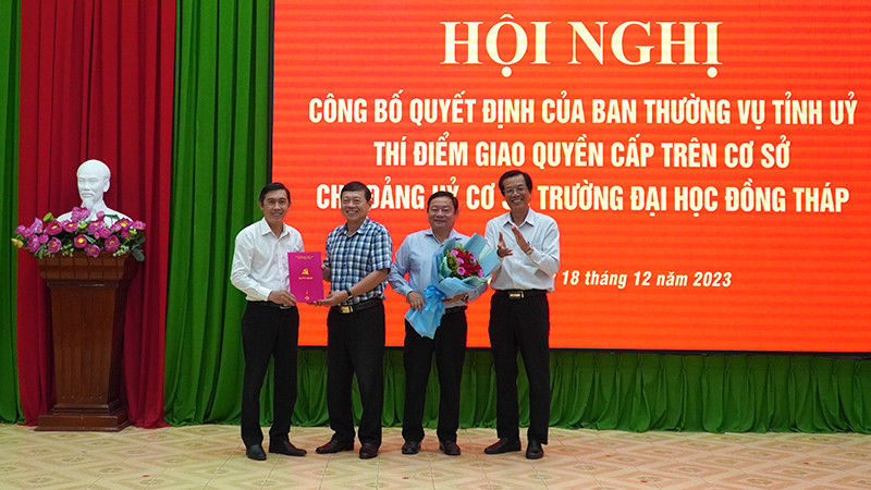 Bí thư Đảng ủy Trường đại học Đồng Tháp Trương Tấn Đạt và Hiệu trưởng Trường đại học Đồng Tháp Hồ Văn Thống nhận Quyết định, hoa của Ban Thường vụ Tỉnh ủy Đồng Tháp. (Ảnh: HỮU NGHĨA)
