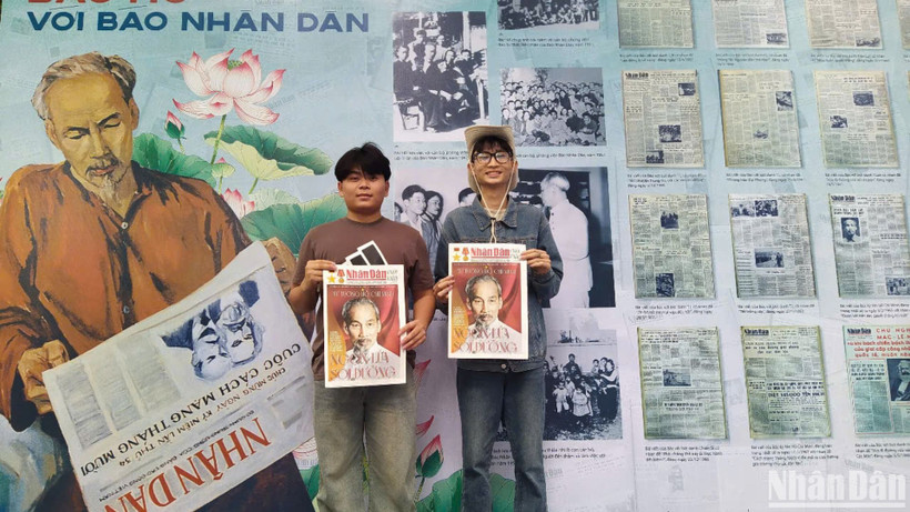 Bạn Nguyễn Đức Tân (đeo kính), sinh viên trường Cao đẳng Du lịch Hà Nội cùng bạn rất vui khi được cầm trên tay tờ báo Nhân Dân cuối tuần số đặc biệt chụp ảnh lưu niệm. (ẢNH: KIM CƯƠNG)
