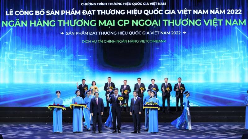 Thủ tướng Chính phủ Phạm Minh Chính (hàng đầu thứ 3 từ trái sang) trao Biểu trưng và đồng chí Nguyễn Hồng Diên - Bộ trưởng Công thương, Chủ tịch Hội đồng Thương hiệu quốc gia Việt Nam (hàng đầu thứ 2 từ phải sang) tặng hoa cho đồng chí Phạm Mạnh Thắng - Phó Tổng Giám đốc Vietcombank.