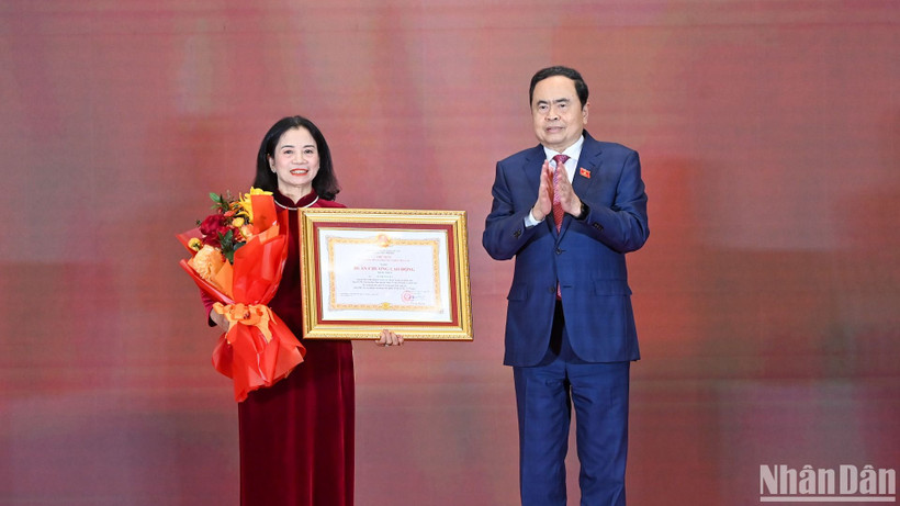 Chủ tịch Quốc hội Trần Thanh Mẫn trao Huân chương Lao động hạng Nhất và tặng hoa chúc mừng đồng chí Lê Thị Nguyệt. (Ảnh: Duy Linh)