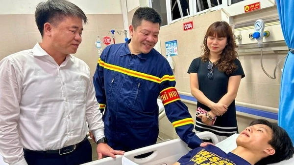 Đại diện Đảng ủy, Ủy ban nhân dân phường Hoàng Mai thăm hỏi, động viên anh Nguyễn Lê Tú, người tham gia giải cứu các nạn nhân vụ cháy tại đường Lĩnh Nam. (Ảnh: Trần Oanh)