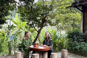 Trung tá Ating Chơn trao đổi với già làng Bríu Pố về công tác giữ gìn an ninh trật tự.
