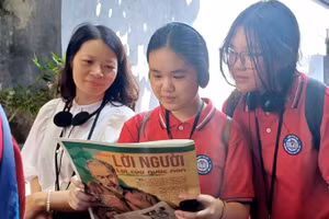 Cô giáo và học sinh trường THCS Chu Văn An (Tây Hồ, Hà Nội) đọc Báo Nhân Dân trong không gian Di tích Nhà tù Hỏa Lò.