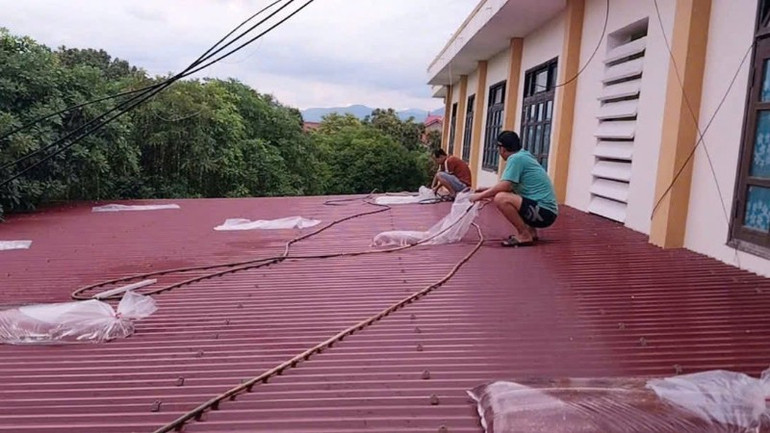 Giáo viên ở phường Đồng Thuận, tỉnh Quảng Trị bơm nước vào các túi ni-lông dày để chắn trên mái tôn nhằm hạn chế thiệt hại do gió bão z6937994572767-0d113577b8a1de47752f3b4c19e1132c-712.jpg