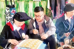 Du khách trải nghiệm nghề truyền thống vẽ sáp ong tại điểm du lịch cộng đồng bản Sưng, xã Cao Sơn.