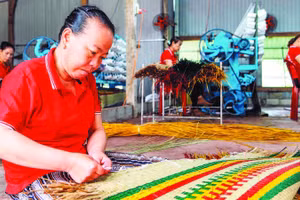 Công nhân Hợp tác xã chiếu cói Hoài Châu Bắc hoàn thiện một công đoạn làm ra chiếc chiếu thành phẩm. (Ảnh MỸ HÀ)