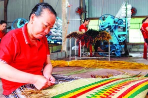 Công nhân Hợp tác xã chiếu cói Hoài Châu Bắc hoàn thiện một công đoạn làm ra chiếc chiếu thành phẩm. (Ảnh MỸ HÀ)
