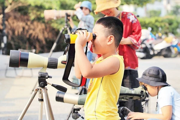 Các em nhỏ trải nghiệm ống nhòm chuyên dụng. 