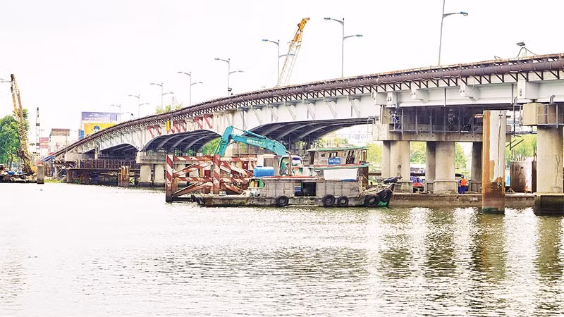 Nâng tĩnh không cầu Bình Triệu 1 nhằm bảo đảm tàu bè lưu thông, vận chuyển hàng hóa thuận tiện trên sông Sài Gòn. (Ảnh THẾ ANH)
