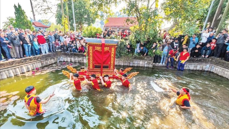 Trai tráng làng Thọ Lộc rước kiệu dưới nước, trước sự cổ vũ của người dân.