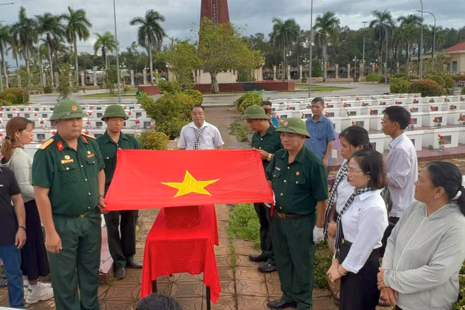 Nghi thức phủ Quốc kỳ, trước khi đưa liệt sĩ Lê Duy Nhẫn về quê hương. (Ảnh: THÀNH TRUNG)