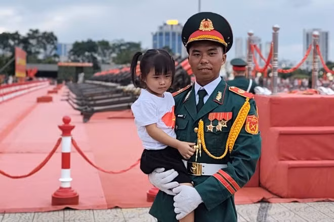Hình ảnh chiến sĩ pháo binh Đỗ Kim Vũ bế cháu gái đến cổ vũ trong chương trình Tổng hợp luyện diễu binh, diễu hành lần 2. (Ảnh: VĂN THỊNH)