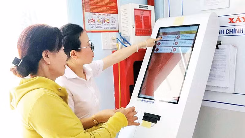 Cán bộ Trung tâm Phục vụ hành chính công xã Hòa Phú hướng dẫn người dân lấy số xếp hàng tự động.