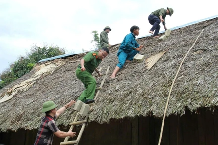 Lực lượng chức năng gia cố mái nhà cho người dân trước bão số 3. (Ảnh: TTXVN)