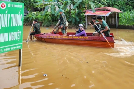 Cán bộ chiến sĩ Bộ Chỉ huy Quân sự tỉnh Lào Cai dùng thuyền đưa dân qua điểm ngập tại Km 27+770, trên Quốc lộ 70. (Ảnh:THANH SƠN)