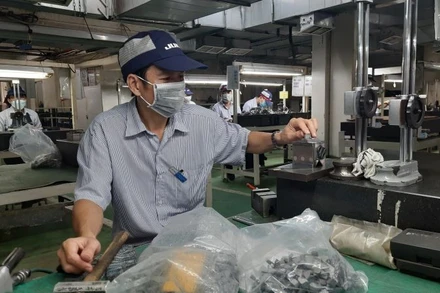 Công nhân Công ty trách nhiệm hữu hạn Juki Việt Nam, Khu Chế xuất Tân Thuận, Thành phố Hồ Chí Minh đang sản xuất các linh kiện máy may công nghiệp.