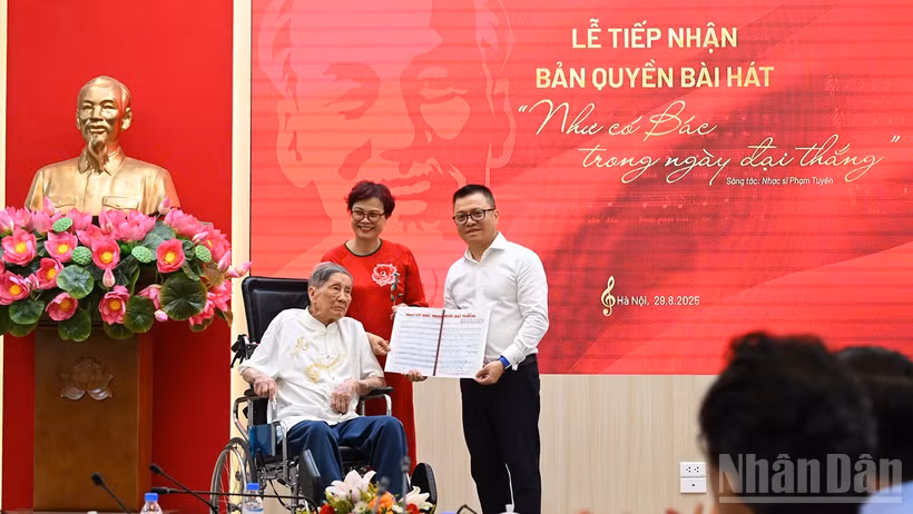 Tổng Biên tập Lê Quốc Minh nhận bản thảo bài hát Như có Bác trong ngày đại thắng có chữ ký đề tặng của nhạc sĩ Phạm Tuyên. (Ảnh: THÀNH ĐẠT)