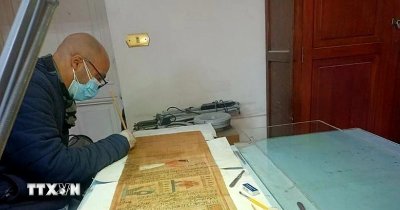 Chuyên gia Phòng thí nghiệm Bảo tồn Giấy cói của bảo tàng đang phục chế cuộn giấy cói của người ghi chép User-Hat-Mes. (Ảnh: TTXVN)