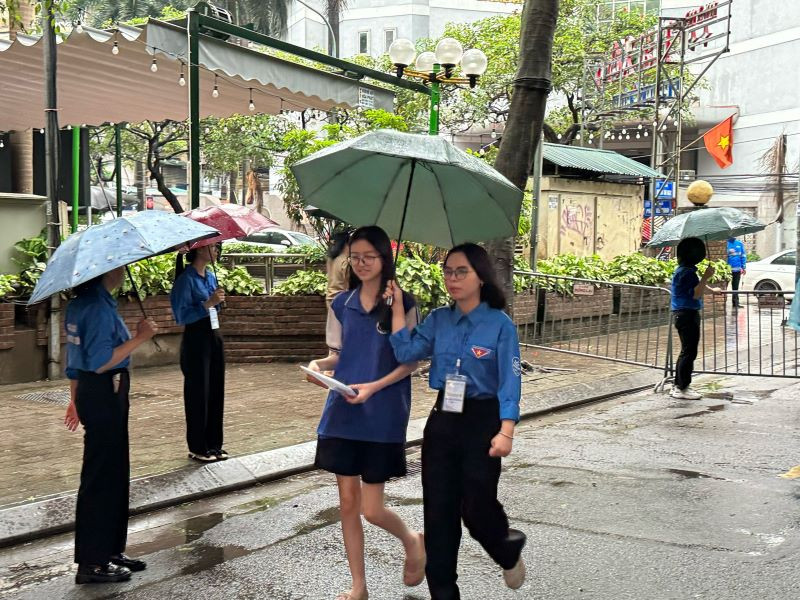 Lực lượng thanh niên tình nguyện hỗ trợ thí sinh dự thi kỳ thi tuyển sinh vào lớp 10 không bị ướt. (Ảnh: KHÁNH THY)