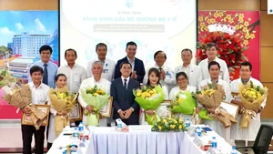 Thứ trưởng Y tế Trần Văn Thuấn tặng hoa và bằng khen cho ekip thực hiện ca can thiệp bào thai cho sản phụ người Singapore. (Ảnh: HOÀNG HÙNG)