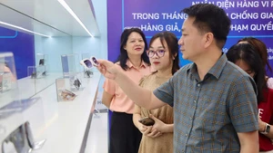 Phó Cục trưởng Quản lý và Phát triển thị trường trong nước (Bộ Công thương) Nguyễn Thanh Bình hướng dẫn người tham quan nhận diện kính mắt hàng giả.