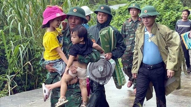 Cán bộ Biên phòng Đồn Ba Nang, tỉnh Quảng Trị, hỗ trợ trẻ nhỏ di dời đến nơi an toàn. Ảnh: TTXVN