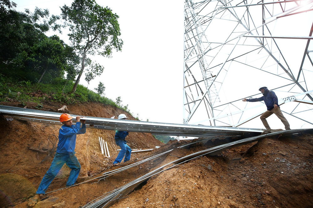 Tranh thủ tạnh mưa, cán bộ công nhân tại vị trí 88 tại huyện Bảo Yên, tỉnh Lào Cai thực hiện lắp các thanh gá dưới chân cột. (Ảnh: LÊ TIÊN) ltt-3988-letien.jpg
