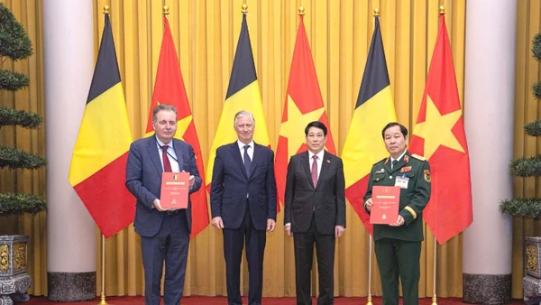 Trung tướng Nguyễn Hữu Chính (ngoài cùng bên phải) và Bộ trưởng, Thủ hiến vùng Brussels, Vương quốc Bỉ (ngoài cùng bên trái) trao đổi Thỏa thuận nguyên tắc về hỗ trợ nạn nhân chất độc da cam Việt Nam, với sự chứng kiến của Nhà vua Philippe (Vương quốc Bỉ) và Chủ tịch nước Lương Cường.