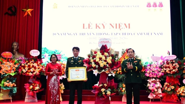 Trung tướng Nguyễn Hữu Chính tặng hoa chúc mừng và trao Bằng khen của Trung ương Hội Nạn nhân chất độc da cam/dioxin Việt Nam cho Tạp chí Da cam Việt Nam. 