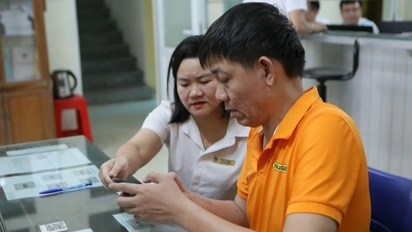 Cán bộ phường hướng dẫn người dân giải quyết thủ tục hành chính thông qua cổng dịch vụ công. (Ảnh: TTXVN)