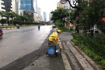 Công nhân Công ty Thoát nước Hà Nội vệ sinh các miệng thu nước trên đường Nguyễn Chí Thanh. (Ảnh: CẢNH HOÀNG)