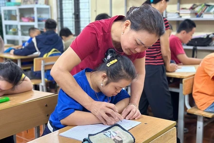 Cô Lê Thị Hòa đang hướng dẫn học sinh viết chữ.