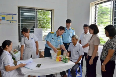 Đại diện lãnh đạo phường Tùng Thiện và Học viện Phòng không-Không quân khám bệnh, cấp thuốc miễn phí cho người có công. 