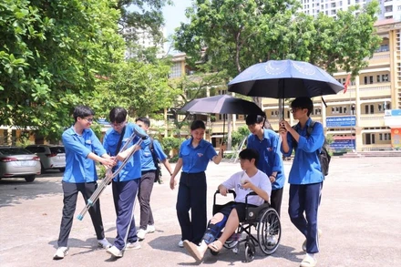 Tình nguyện viên tại điểm thi Trường THPT Nhân Chính hỗ trợ thí sinh bị gãy chân lên phòng thi.