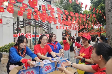 Các bạn tình nguyện viên phát nước cho người dân đi xem sơ duyệt diễu binh, diễu hành tại Hà Nội. (Ảnh: THẾ ĐẠI)