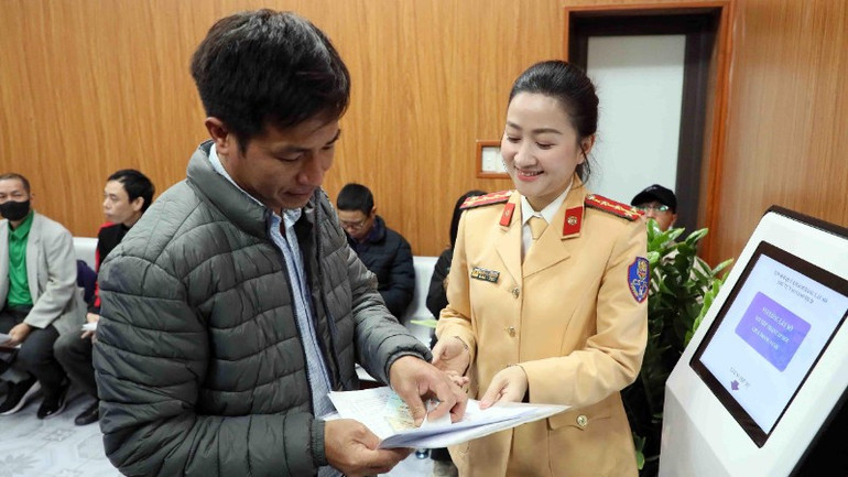 Cán bộ Đội sát hạch, cấp giấy phép lái xe cơ giới đường bộ (Phòng Cảnh sát giao thông, Công an thành phố Hà Nội) hướng dẫn người dân thực hiện thủ tục hành chính. (Ảnh: THANH HÀ) 3-3-giay-phep-3-4679.jpg