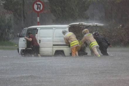 Đường phố ngập sâu, cảnh sát giao thông dầm mưa cùng người dân di chuyển phương tiện đến nơi an toàn.