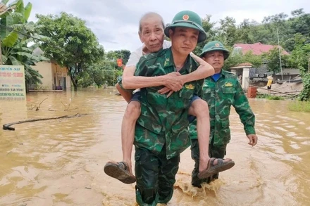 Bộ đội Biên phòng Tam Quang cõng đưa một cụ ông đến nơi an toàn. (Ảnh: HẢI THƯỢNG)