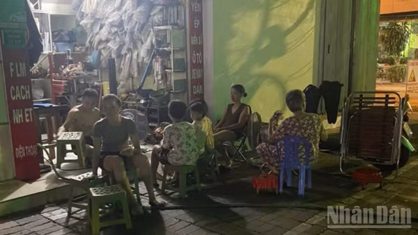 Người dân trên phố Hai Bà Trưng (phường Thái Bình, tỉnh Hưng Yên) dùng đèn ắc quy ngồi chờ trong lúc bị ngừng cấp điện.