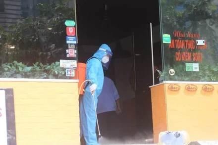 Đội phản ứng nhanh của Trung tâm y tế quận Cầu Giấy phun khử khuẩn tại quán pizza 106 Trần Thái Tông, nơi bệnh nhân N.T.H làm việc. (Ảnh: NAM TIẾN)