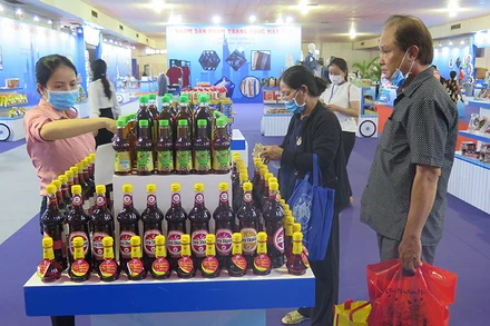 Người dân tham quan, mua sắm hàng hóa tại một gian hàng ở Hội chợ – Triển lãm trong tối ngày 29-7.