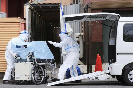 Nhân viên y tế đưa người bệnh Covid-19 thể nhẹ tới cách ly tại khách sạn ở TP Gifu, Nhật Bản. (Ảnh: Kyodo)