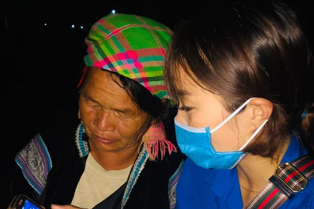 Thanh niên tình nguyện hướng dẫn một người dân tộc thiểu số ở Lai Châu cài đặt Bluezone.