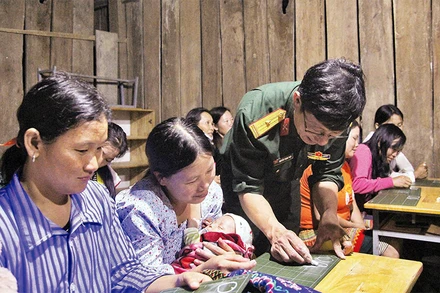 Thiếu tá Nguyễn Trọng Thúy hướng dẫn cho bà con Tiểu khu 179 viết chữ.