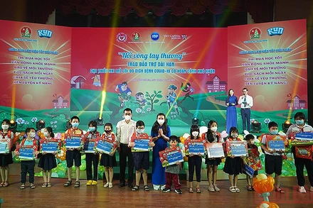 Đồng chí Nguyễn Phạm Duy Trang (áo xanh) và đại diện các đơn vị liên quan trao bảo trợ dài hạn tặng thiếu nhi mồ côi do đại dịch Covid-19.